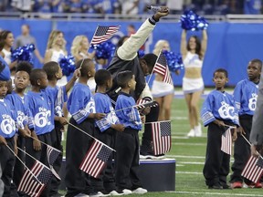 FILE- In a file photo from Sept. 24, 2017, National anthem singer Rico Lavelle bends to his knee, bows his head and raises his fist after singing the anthem before the first half of an NFL football game between the Detroit Lions and the Atlanta Falcons in Detroit. The sight of football players kneeling during the national anthem is the continuation of a tradition nearly as old the song itself. University of Michigan musicology professor Mark Clague says "The Star-Spangled Banner" has been a channel for protest since at least the 1840s. The lyrics were recast as an anti-slavery song and it's been used or reworked to push for racial equality, women's suffrage, prohibition and labor rights. (AP Photo/Carlos Osorio, File)