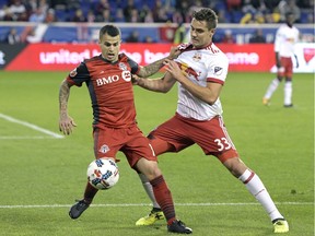 Toronto FC forward Sebastian Giovinco, left, holds off New York Red Bulls midfielder Aaron Long during the second half of an MLS Eastern Conference semifinal soccer match in Harrison, N.J., on Monday night. Toronto FC won 2-1. AP Photo/Bill Kostroun