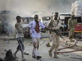 A Somali soldier helps a civilian who was wounded in a blast in the capital of Mogadishu, Somalia, Saturday, Oct. 14, 2017.