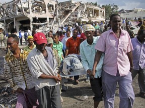 Somalis remove the body of a man killed in Saturday's blast, in Mogadishu, Somalia Sunday, Oct. 15, 2017. The death toll from the huge truck bomb blast in Somalia's capital rose to over 50 Sunday, with more than 60 others injured, as hospitals struggled to cope with the high number of casualties, security and medical sources said. (AP Photo/Farah Abdi Warsameh)