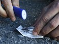 An Ottawa user prepares an opioid pill to inject behind a downtown church.