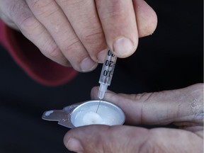 A drug user prepares o inject behind a downtown church in Ottawa. Photo: Tony Caldwell