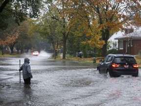 Junior Belmaeda tries to clear the leaves off the sewer grate on Sanderson Drive during a rain storm in Ottawa Monday Oct. 30, 2017.