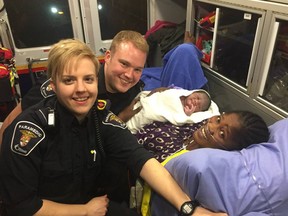 Paramedics Matt Friesen and Courtney Healey with a healthy mom and baby after an early roadside delivery Wednesday.
