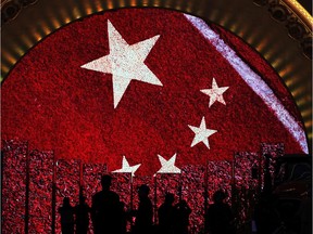 In this Monday, Oct. 23, 2017, file photo, visitors is silhouetted as they watch a video display boards showing the Chinese flag at an exhibition highlighting China's achievements under five years of leadership by Chinese President Xi Jinping at the Beijing Exhibition Hall in the capital city where the 19th Party Congress is held in Beijing. (AP Photo/Andy Wong, File) ORG XMIT: ASIA501

OCT. 23, 2017 FILE PHOTO
Andy Wong, AP