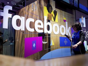 In this Tuesday, April 18, 2017, file photo, a conference worker passes a demo booth at Facebook's annual F8 developer conference in San Jose, Calif.