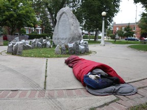 A homeless man sleeps in a city park off Elgin Street. Ottawa needs long-term thinking about housing.