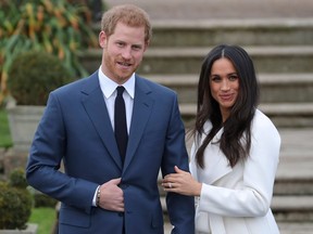 Britain's Prince Harry stands with his fiancée Meghan Markle as she shows off her engagement ring while they pose for a photograph in the Sunken Garden at Kensington Palace in west London on November 27, 2017, following the announcement of their engagement.