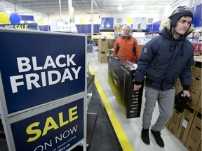 Customers carry a television at Best Buy on Black Friday in Ottawa on November 25, 2016.