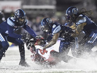 Toronto Argonauts defensive back Jermaine Gabriel (5) linebacker Marcus Ball (6) and defensive back Qudarius Ford (21) tackle Calgary Stampeders running back Roy Finch (14) during second half CFL football action in the 105th Grey Cup on Sunday, November 26, 2017 in Ottawa.