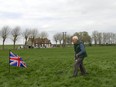 In this photo taken on Monday, April 22, 2013, amateur archeologist and historian Moise Dilly runs a metal detector over the area in which he located the bodies of two British World War I soldiers in 2009 in a field in Bullecourt, France.