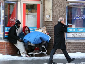 Homeless men watch passersby on Elgin Street in downtown Ottawa.