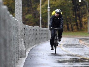 A cyclist rides along the Rideau Canal pathway in the rain.
