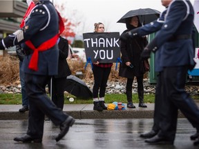 A woman holds a sign while the funeral procession carrying the body of Abbotsford Police Const. John Davidson, who was killed in the line of duty on Nov. 6, makes its way to a memorial in Abbotsford on Sunday.