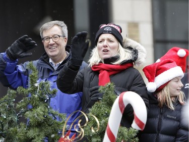 Catherine McKenna and Mayor Jim Watson wave to crowds during the annual Help Santa Toy Parade, which made its way through downtown Ottawa featuring familiar festive floats, marching bands, city councillors, firefighters and more, with volunteers collecting toys for less fortunate children along the way, on Saturday, Nov. 18, 2017