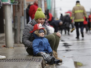 Turner Brandt and his mom Erin watch the annual Help Santa Toy Parade, which made its way through downtown Ottawa featuring familiar festive floats, marching bands, city councillors, firefighters and more, with volunteers collecting toys for less fortunate children along the way, on Saturday, Nov. 18, 2017.