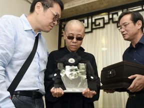 In this July 15, 2017, file photo provided by the Shenyang Municipal Information Office, Liu Xia, center, wife of jailed Nobel Peace Prize winner and Chinese dissident Liu Xiaobo, holds a portrait of him during his funeral at a funeral parlor in Shenyang in northeastern China's Liaoning Province. For many in the rights community, the death of imprisoned Liu Xiaobo from liver cancer in July represented a nadir of sorts. Despite his 11-year sentence on charges of incitement to subvert government power, Liu had remained a symbol of courage and persistence in his belief in a democratic China. His widow, Liu Xia, had been held a virtual prisoner in her Beijing home throughout Liu's sentence, despite never being charged. Since his death, she's had virtually no contact with friends or family and the authorities will not say where she is currently being held. (Shenyang Municipal Information Office via AP, File)