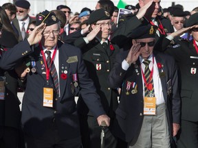 Canadian veterans salute during the playing of the national anthems at the end of a ceremony marking the 100th anniversary of the Battle of Vimy Ridge near Arras, France, Sunday, April 9, 2017.