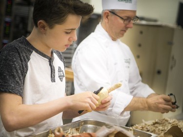 Volunteers, students and chefs were busy preparing a festive meal in support of Operation Big Turkey at the Algonquin College School of Hospitality Kitchen Saturday December 23, 2017. The thirteenth year of Operation Big Turkey has over 200 volunteers coming together to make 2500 turkey dinners to anyone who would like to have a meal.  L-R 13-year-old Ryan Haskins and Algonquin culinary management program co-ordinator Cory Haskins were busy peeling potatoes Saturday morning.   Ashley Fraser/Postmedia