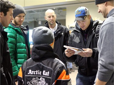 A number of Ottawa Senators and other NHL players arrived in Yellowknife in the Northwest Territories Sunday to begin their Northern Lights Dream Tour, which will include three exhibition games in Yellowknife, Inuvik, and Whitehorse (Yukon). Here,  Ottawa Senator Chris Neil signs an autograph for a young fan at the airport as (from left:) Dartmouth College goalie Jody O'Neil, -Peter Regin, goalie Craig Anderson and Marc Methot look on.