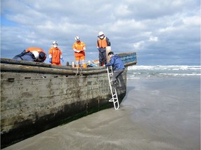 This handout picture taken on November 27, 2017 by the Oga city municipal office and released via Jiji Press shows coast guard officers inspecting a battered wooden boat where eight bodies were found inside at a beach in Oga, Japan's Akita prefecture. Japanese coastguard officials spotted eight bodies inside a battered wooden boat off northern Akita prefecture but waves had prevented officials from investigating since the boat was first spotted on November 24. Dozens of North Korean fishing vessels wash up on Japan's coast every year. Sometimes the boats' occupants have already died at sea, a phenomenon local media refer to as "ghost ships".