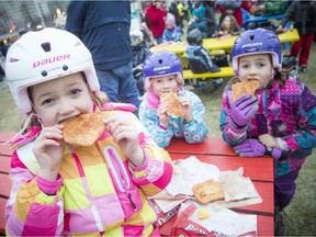 Six-year-old Sabine Burchill, twin sister Bianca and big sister seven-year-old Indira bite into some Beavertails at the Mayor's Annual Christmas Celebration at City Hall on Saturday. The Birchells just moved to Canada's from Australia and are spending their first holiday season in Ottawa.