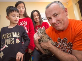 The Gibson family, from left, Grayson Gibson, 6, Hannah Gibson, 8, Hwehkyung Kim and John Gibson, take part in the Ottawa Humane Society's Holiday Delivery Program where parents adopt a pet through the regular adoption process - and a volunteer elf delivers the pet to the family home on Christmas morning. They received a kitten they named Sunshine.