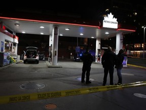 Ottawa police officers patrol in front of the cordoned-off area at the service station at the intersection of King Edward Avenue and Rideau Street on Friday night. David Kawai/Postmedia