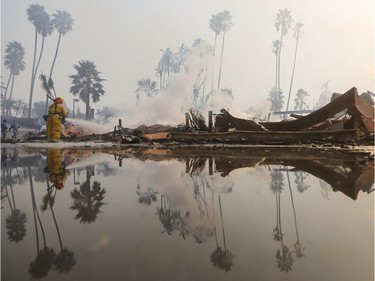 VENTURA, CA - DECEMBER 05:  A firefighter sprays water at the remains of an apartment complex destroyed by the Thomas Fire on December 5, 2017 in Ventura, California. Around 45,000 acres have burned in the fire forcing thousands to evacuate and destroying 150 structures.