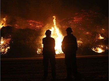 VENTURA, CA - DECEMBER 07:  Firefighters monitor a section of the Thomas Fire along the 101 freeway on December 7, 2017 north of Ventura, California. Strong Santa Ana winds are rapidly pushing multiple wildfires across the region, expanding across tens of thousands of acres and destroying hundreds of homes and structures.