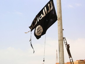 This file photo taken on April 30, 2017 shows a member of the US-backed Syrian Democratic Forces (SDF), made up of an alliance of Arab and Kurdish fighters, removing an Islamic State group flag in the town of Tabqa.