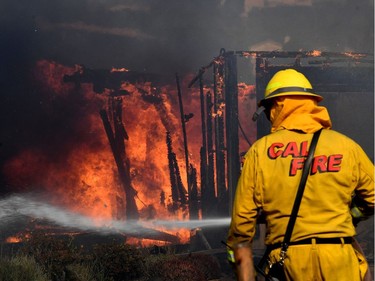 Firefighters battle strong winds as they try to save a house during the Thomas wildfire in Ventura, California, on December 5, 2017. Firefighters battled a wind-whipped brush fire in southern California that has left at least one person dead, destroyed more than 150 homes and businesses and forced tens of thousands to flee.