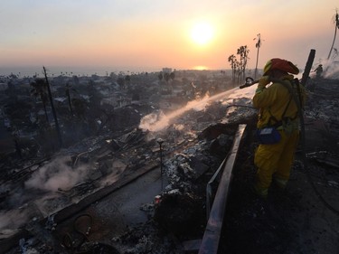 A firefighter hoses down flareups at the two story Hawaiian Village Apartment complex that burnt to the ground during the Thomas wildfire in Ventura, California on December 5, 2017. Firefighters battled a wind-whipped brush fire in southern California that has left at least one person dead, destroyed more than 150 homes and businesses and forced tens of thousands to flee.