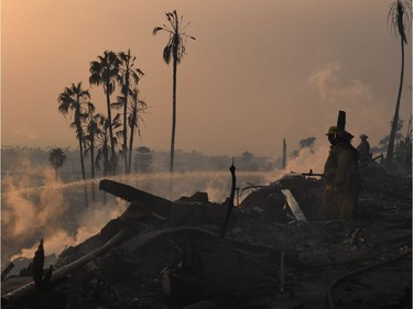 Firefighters hose down flareups at the two story Hawaiian Village Apartment complex that burnt to the ground during the Thomas wildfire in Ventura, California on December 5, 2017. Firefighters battled a wind-whipped brush fire in southern California that has left at least one person dead, destroyed more than 150 homes and businesses and forced tens of thousands to flee.