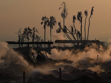 A firefighter hoses down flareups at the two story Hawaiian Village Apartment complex that burnt to the ground during the Thomas wildfire in Ventura, California on December 5, 2017. Firefighters battled a wind-whipped brush fire in southern California that has left at least one person dead, destroyed more than 150 homes and businesses and forced tens of thousands to flee.