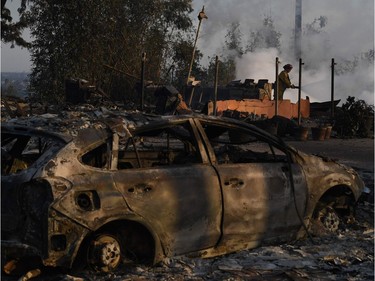 A firefighter hoses down flareups at the two story Hawaiian Village Apartment complex that burnt to the ground during the Thomas wildfire in Ventura, California on December 5, 2017. Firefighters battled a wind-whipped brush fire in southern California that has left at least one person dead, destroyed more than 150 homes and businesses and forced tens of thousands to flee.