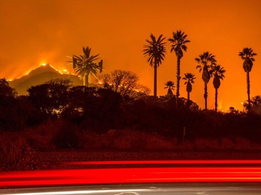 TOPSHOT - The Thomas Fire burns along a hillside near Santa Paula, California, on December 5, 2017. More than a thousand firefighters were struggling to contain a wind-whipped brush fire in southern California on December 5 that has left at least one person dead, sent thousands fleeing, and was choking the area with thick black smoke.