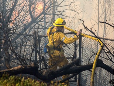 Firefighters work to save burning houses along Linda Flora Drive during the Skirball Fire in Los Angeles, California, December 6, 2017. The "Skirball" fire ignited before 5 a.m. (1300 GMT) and quickly engulfed some 50 acres, with forecasters predicting the 25-mile-per-hour winds could cause further spreading, threatening multi-million dollar homes and the acclaimed Getty Center museum.