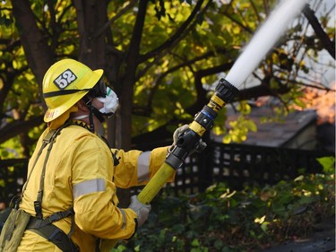 A firefighter controls flames burning in a home at the Skirball Fire in the upscale Bel Aire section of west Los Angeles, California, December 6, 2017. California motorists commuted past a blazing inferno Wednesday as wind-whipped wildfires raged across the Los Angeles region, with flames  triggering the closure of a major freeway and mandatory evacuations in an area dotted with mansions.