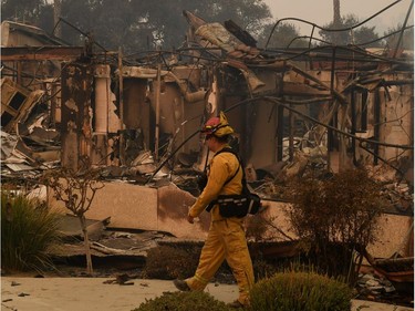 A firefighter walks past the burnt out Vista del Mar Hospital after the Thomas wildfire swept through Ventura, California on December 6, 2017. California motorists commuted past a blazing inferno Wednesday as wind-whipped wildfires raged across the Los Angeles region, with flames  triggering the closure of a major freeway and mandatory evacuations in an area dotted with mansions.