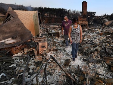John and Julie Wilson sort through the remnants of their burnt out home after the Thomas wildfire swept through Ventura, California on December 6, 2017.  California motorists commuted past a blazing inferno Wednesday as wind-whipped wildfires raged across the Los Angeles region, with flames  triggering the closure of a major freeway and mandatory evacuations in an area dotted with mansions.