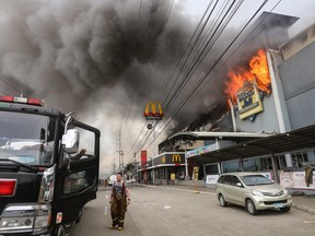 A firefighter standing in front of the burning shopping mall in Davao City on the southern Philippine island of Mindanao.