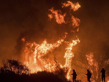 Motorists on Highway 101 watch flames from the Thomas fire leap above the roadway north of Ventura, Calif., on Wednesday, Dec. 6, 2017.  As many as five fires have closed highways, schools and museums, shut down production of TV series and cast a hazardous haze over the region. About 200,000 people were under evacuation orders. No deaths and only a few injuries were reported.