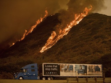 Flames from the Thomas fire burn above a truck on Highway 101 north of Ventura, Calif., on Wednesday, Dec. 6, 2017.