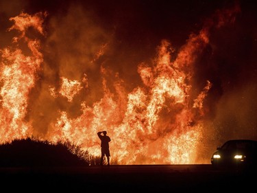 A motorists on Highway 101 watches flames from the Thomas fire leap above the roadway north of Ventura, Calif., on Wednesday, Dec. 6, 2017.  As many as five fires have closed highways, schools and museums, shut down production of TV series and cast a hazardous haze over the region. About 200,000 people were under evacuation orders. No deaths and only a few injuries were reported.