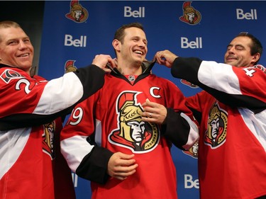 Ottawa Senators' Jason Spezza (centre) has his captain's team jersey adjusted by assistant captains Chris Neil (left) and Chris Phillips (right) after he was named the team's captain in Ottawa, Saturday Sept. 14, 2013.