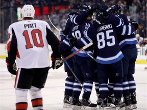 The Winnipeg Jets celebrate a goal by Tyler Myers (obscured) as Ottawa Senators' Tom Pyatt (10) looks on during second period NHL hockey action in Winnipeg, Sunday, December 3, 2017.