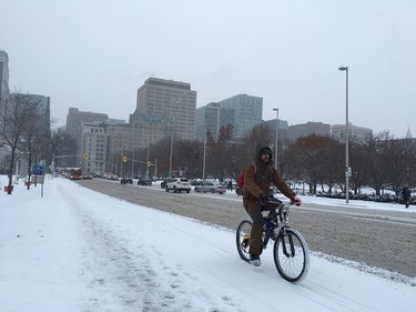A hearty cyclist bikes eastward along Laurier Avenue on Tuesday morning after the winter’s first substantial snowfall.