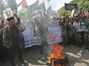 Muslim men burn a tire as they shout slogans during a protest against U.S.President Donald Trump's decision to recognize Jerusalem as Israel's capital outside the U.S. Embassy in Jakarta, Indonesia, Friday, Dec. 8, 2017.