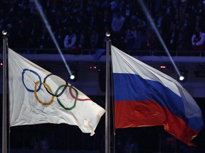 FILE - In this Feb. 23, 2014 file photo, the Russian national flag, right, flies after next to the Olympic flag during the closing ceremony of the 2014 Winter Olympics in Sochi, Russia. Russia could be banned from competing at the Pyeongchang Olympics. The decision will come on Tuesday, Dec. 5, 2017 when the International Olympic Committee executive board meets in Lausanne, less than nine weeks before the games open on Feb. 9 in South Korea.